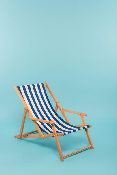 silla de cubierta rayada sobre fondo azul  - Foto, imagen