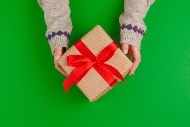Woman hands holding gift box on green background - Foto, immagini