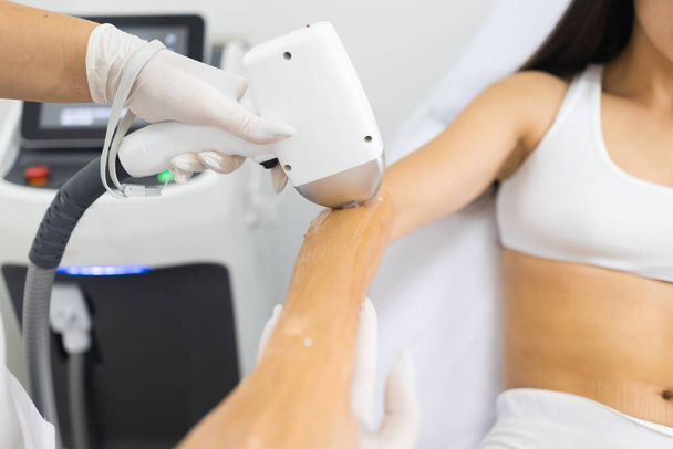 Arzt macht brünette Frau in weißer Unterwäsche eine Laser-Haarentfernung - Foto, Bild