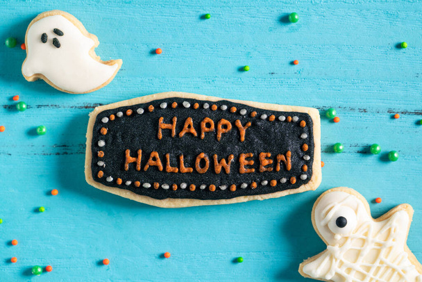 Top view of Halloween festive decorated baked icing gingerbread sugar cookies on blue background with copy space and flat lay. - Fotografie, Obrázek