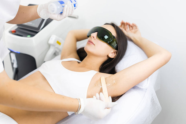 Cosmetologist aplica gel para remoção de cabelo a laser para axila mulher - Foto, Imagem