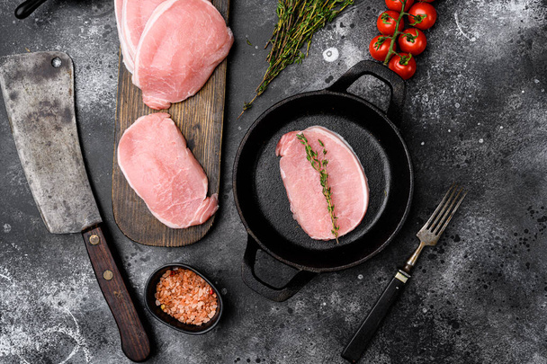 Sliced raw pork meat set, on frying cast iron pan, on black dark stone table background, top view flat lay - Photo, Image