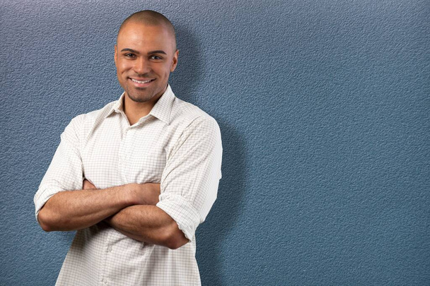 Handsome mid adult man looking at camera against the wall and smiling. - Photo, image