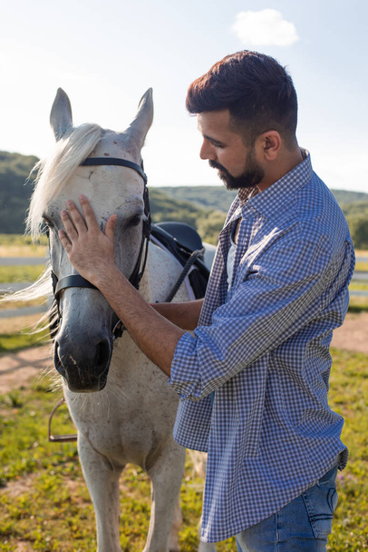 The handsome man is looking into the eyes of a horse - Foto, Imagen