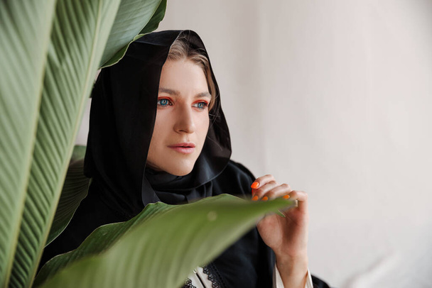 Piękna muzułmanka w tradycyjnej arabskiej sukience abaja na szarym tle. Wysokiej jakości zdjęcie - Zdjęcie, obraz