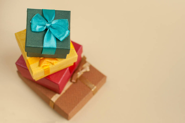 gift boxes in blue, yellow, red and brown colors in the form of a slide with a blurred background on a beige background with a place for text - Фото, зображення