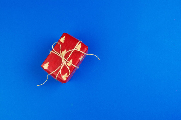 Flat lay of gift box decorated with bow on blue background - Фото, изображение
