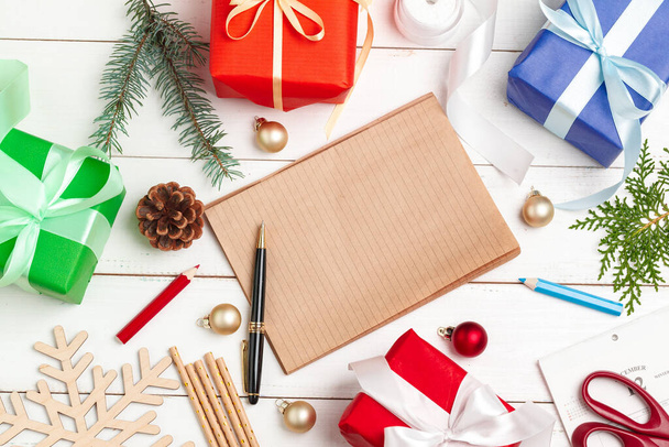 Γράφω ευχετήριες κάρτες Χριστουγέννων. Άνοιγμα σημειωματάριο με στυλό σε διακοσμημένο ξύλινο τραπέζι - Φωτογραφία, εικόνα