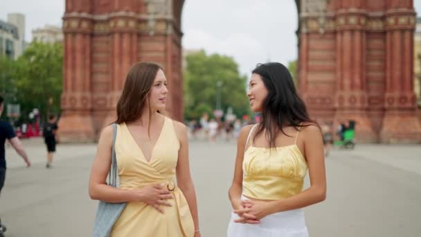 Zwei junge schöne Frauen unterschiedlicher Rassen Freundinnen unterhalten sich fröhlich beim Spazierengehen im Freien - Filmmaterial, Video