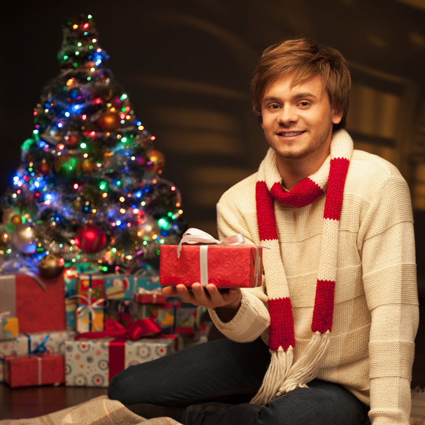 young smiling man holding red christmas gift - Fotografie, Obrázek