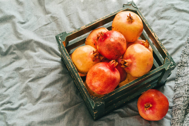 Fresh pomegranates in an old box on wooden background - Φωτογραφία, εικόνα