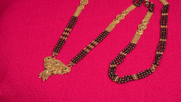 Mangalsutra ή χρυσό κολιέ για να φορέσει από έναν παντρεμένο Ινδουιστές γυναίκες, που διοργανώνονται με όμορφο φόντο. Ινδικό παραδοσιακό κόσμημα. - Φωτογραφία, εικόνα