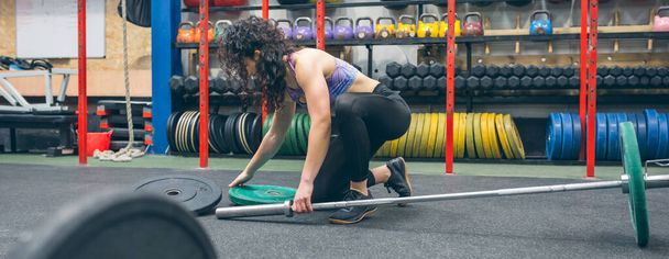 Женщина меняет диски штанги для тяжелой атлетики - Фото, изображение
