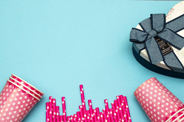 dziewczyna urodziny koncepcja strony, jednorazowe kubki i słomki z pudełka dar serca na niebieskim tle - Zdjęcie, obraz