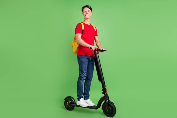 Full length photo of young guy happy positive smile ride electric scooter trip isolated over green color background - Photo, image