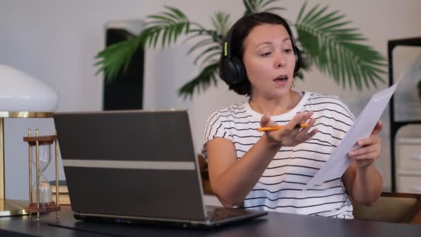 Mujer joven lleva auriculares conferencia de llamadas en las conversaciones portátiles con el profesor en línea que estudia, trabajando desde casa
. - Imágenes, Vídeo