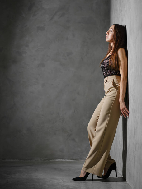 Middle age woman in wide trousers leaning to the wall - Fotoğraf, Görsel