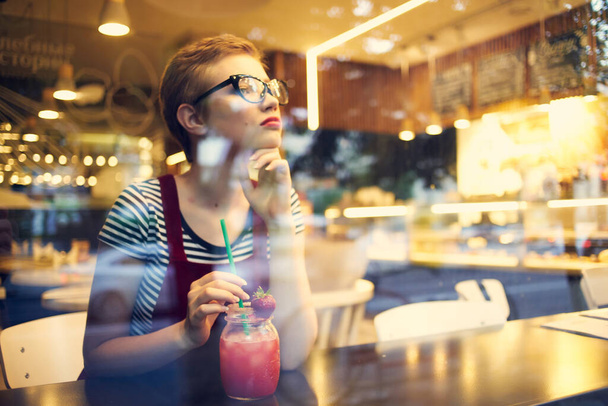 mujer sentada en un restaurante con un cóctel soledad mirada pensativa - Foto, Imagen