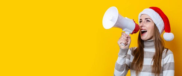 Young woman talking into a megaphone on a yellow background. Banner.  - Photo, Image