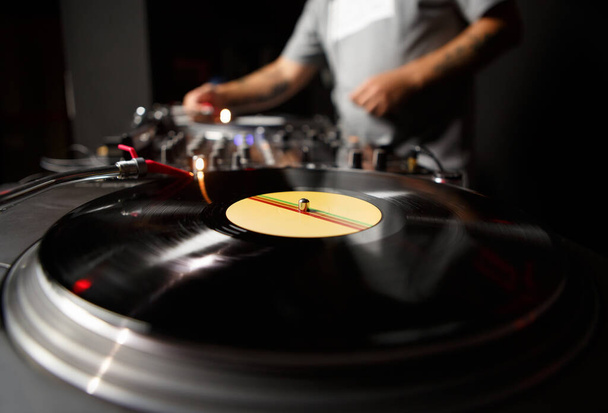 Hip Hop dj plays music with vinyl turntables. Professional disc jockey mixing musical tracks on stage in night club - Fotó, kép