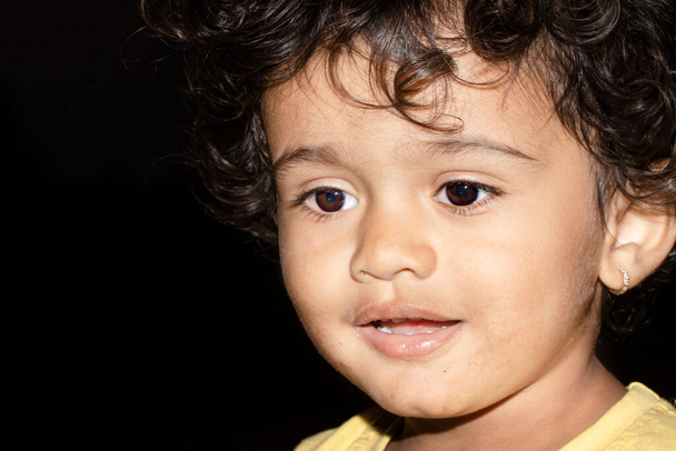 Nahaufnahme Gesicht Foto eines jungen indischen Kindes im Gespräch mit schwarzen isoliert niedrigen Hintergrund, Indien - Foto, Bild