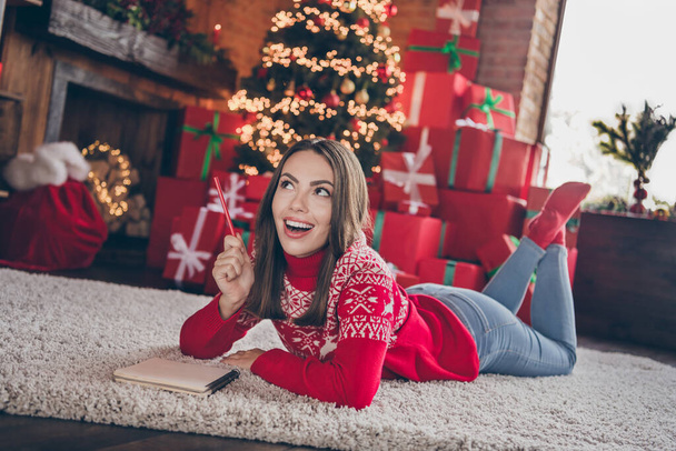 Full body photo of impressed millennial lady lie on floor think wishes wear new year sweater jeans socks at home alone on christmas eve - Fotoğraf, Görsel