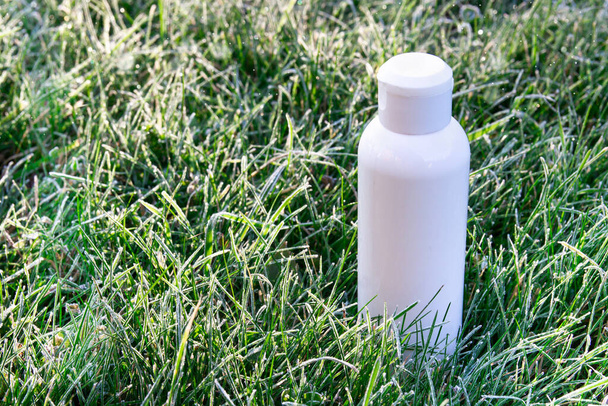 there is a white bottle in the grass with frost and dew drops. aroma of morning freshness  - Foto, immagini