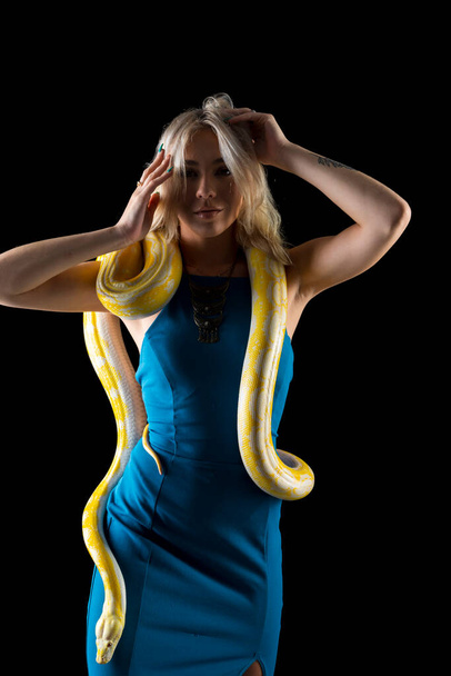 Una hermosa modelo rubia posa con una serpiente Boa en un ambiente de estudio - Foto, Imagen