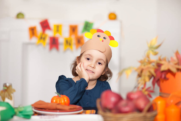 Little cute girl sitting on festive table and celebrating Thanksgiving day. - Фото, зображення
