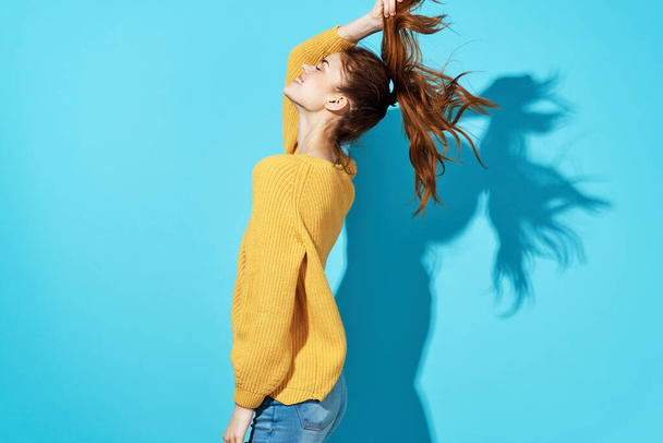 red-haired woman in yellow sweater holding hair fashion blue background - Fotografie, Obrázek
