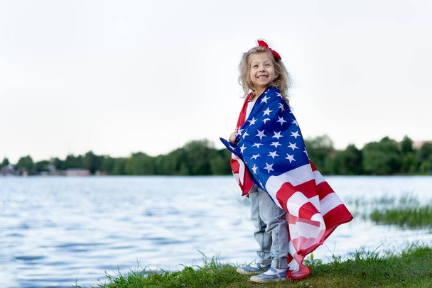 holčička s americkou vlajkou v přírodě, koncept vlastenectví a svátek nezávislosti USA. Veterans Day USA. - Fotografie, Obrázek
