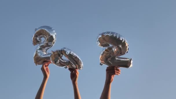 Mani alzare palloncini in forma di numeri 2022 contro il cielo blu - Filmati, video