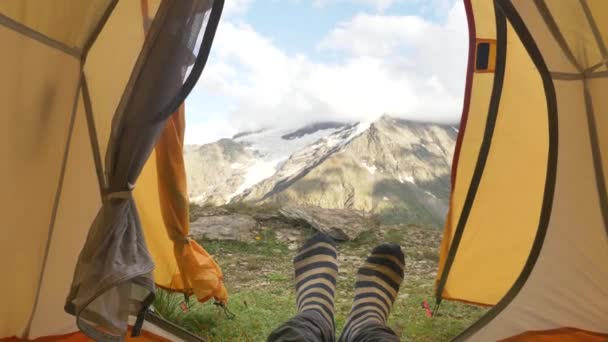 A személy sárga sátorban fekszik, és színes zokniban mozgatja a lábát. - Felvétel, videó