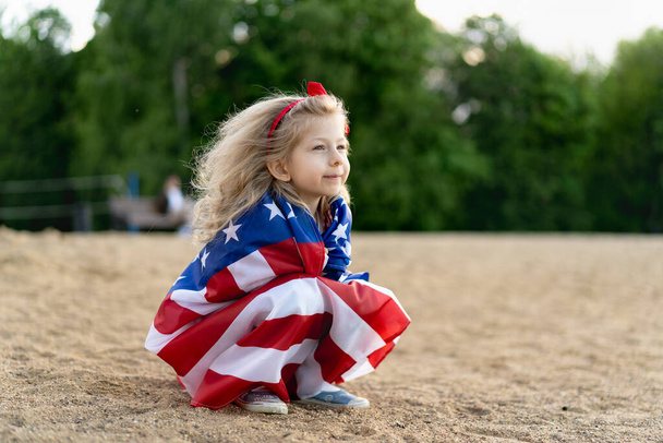 κοριτσάκι με την αμερικανική σημαία στη φύση, την έννοια του πατριωτισμού και την αργία της ανεξαρτησίας των ΗΠΑ. Ημέρα Βετεράνων ΗΠΑ - Φωτογραφία, εικόνα