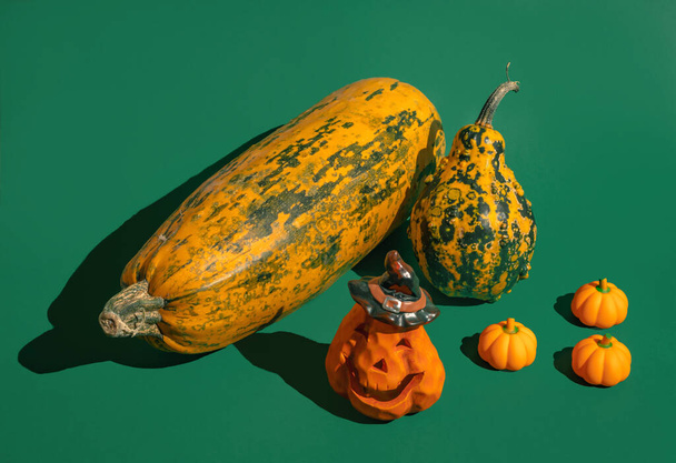 Pumpkins, halloween pumpkin lantern amnd little rubber pumpkins stand on pastel green background. Minimal autumn halloween celebration concept - Zdjęcie, obraz