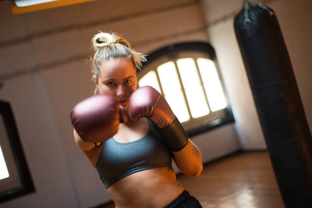 Pretty young sportswoman in boxing gloves - 写真・画像