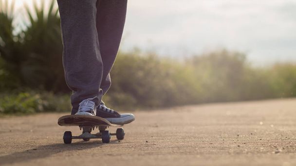Un giovane uomo è felice di pattinare su una strada di campagna da solo per praticare le sue abilità di pattinaggio e divertirsi. Skate surf pratica idee nel tempo libero per prepararsi alle competizioni. - Foto, immagini