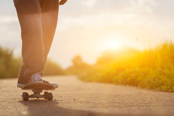 A young man is happily skating down a country road alone to practice his skating skills and have a fun break. Skate surfing skills practice ideas in your spare time to prepare for competitions. - Photo, Image