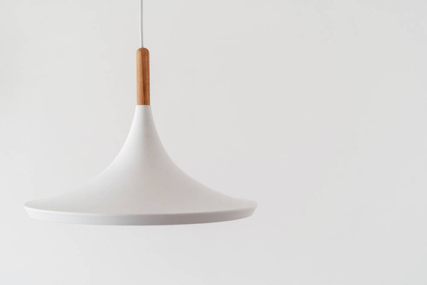 Moderní bílá stropní lampa zavěšená na kopírovací stěně v světlém obývacím pokoji s minimalistickým designem interiéru. Koncept elektrického zařízení a osvětlení v ložnici - Fotografie, Obrázek