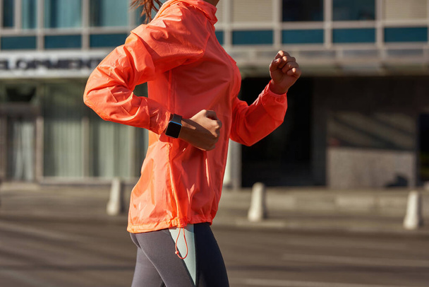 Close up of sporty woman run outside with device - Fotó, kép