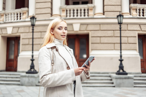 Nuori blondi nainen käyttää älypuhelinta kaupungissa - Valokuva, kuva