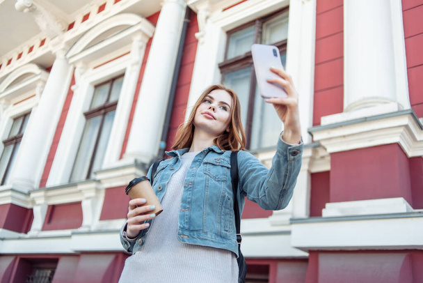 Cute beautiful caucasian woman taking a selfie on a smartphone in the city - Fotografie, Obrázek