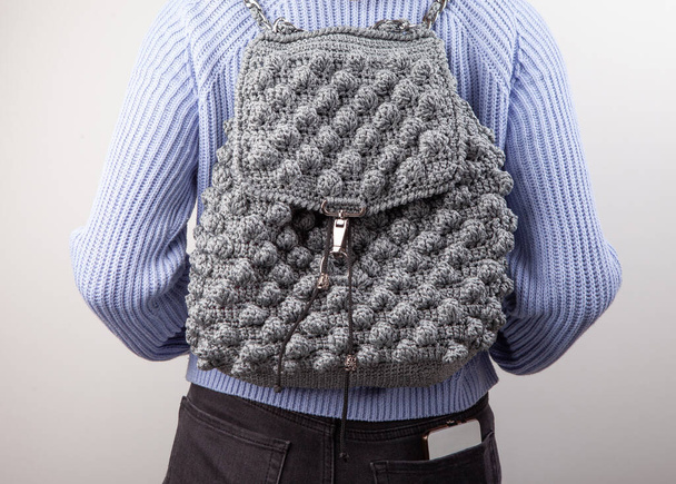 Woman with knitted backpack on gray background - Photo, Image