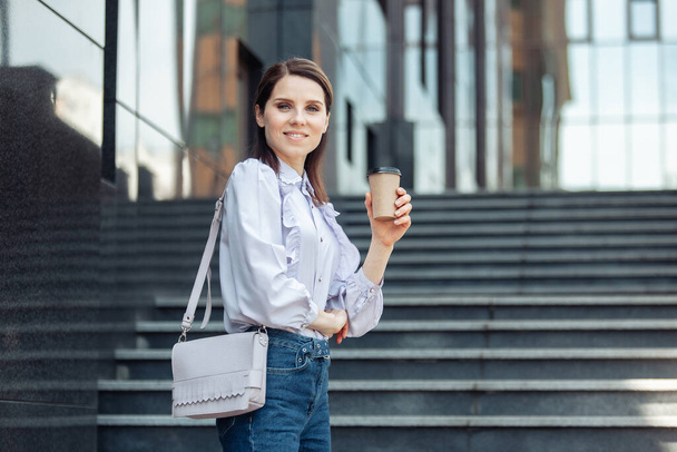 Sorrindo mulher de negócios segurando xícara de café em movimento - Foto, Imagem