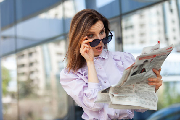 ビジネスセンターの背景に新聞を読んで驚くべきビジネス女性 - 写真・画像