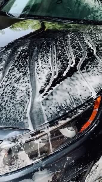 Ajoneuvo, jossa on vettä ja saippuaa ja joka virtaa autonpesuasemalla - Materiaali, video