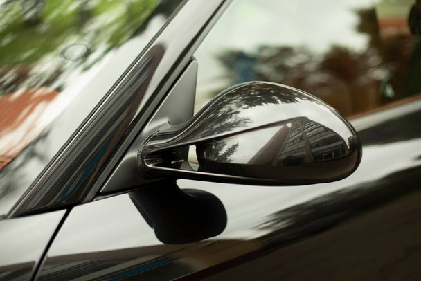 Rear-view mirror of an expensive car. Machine parts. Black transport. Glossy car open. - Foto, Imagen