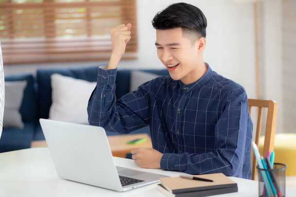 Boldog fiatal üzletember dolgozik laptop számítógép befejezni izgatott és sikeres az asztalon otthon, üzletember segítségével notebook teljesítmény és meglepett, szabadúszó vagy alkalmazott, elégedett és boldog. - Fotó, kép