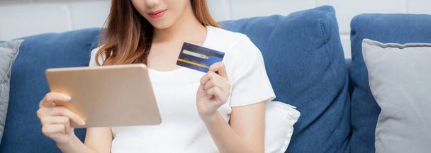Junge asiatische Frau lächelt und hält Kreditkarteneinkauf online mit Tablet-Computer Kauf und Zahlung, Mädchen mit Debitkarte Kauf oder Transaktion von Finanzen, Lifestyle und E-Commerce-Konzept. - Foto, Bild
