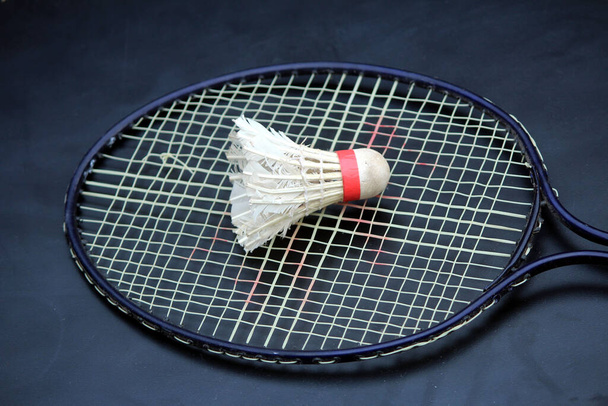 a shuttle cock on a racket with light black background - Foto, imagen